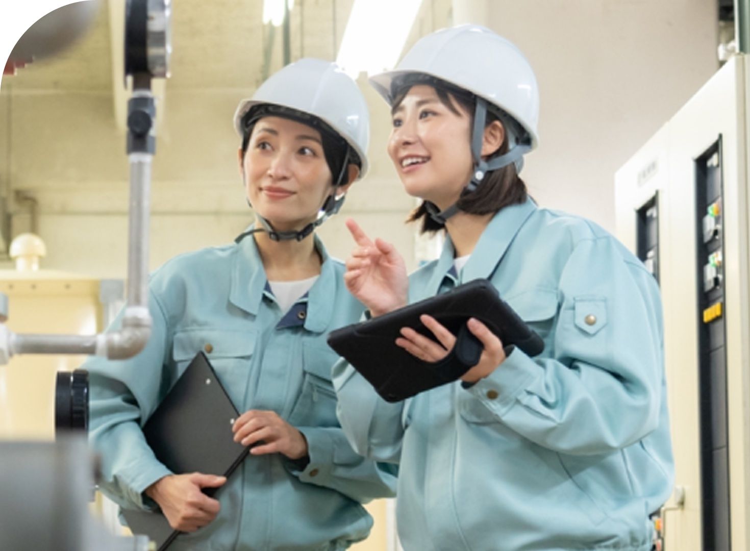 ヘルメットを着用しタブレットを手にした2名のIESスタッフが工場設備を点検している様子